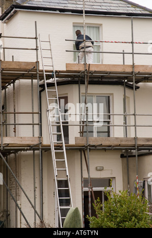 Man Painting fenêtre sur un échafaudage en uk Banque D'Images