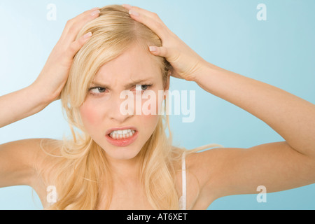 Jeune femme tenant sa tête dans les expressions de frustration, portrait Banque D'Images