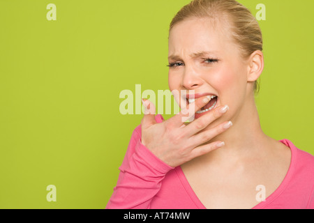 Femme sentant ses dent avec son doigt, portrait Banque D'Images