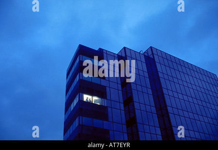 La façade d'un immeuble dans la nuit avec un seul bureau du coin de lumière sur Banque D'Images