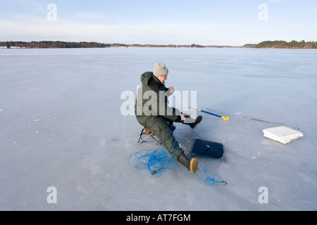 Contrôle de la pêche les filets de pêche à l'hiver sur la glace du lac Finlande Banque D'Images