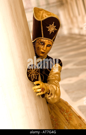 Carnaval de Venise DAME PORTANT MASQUE D'OR, D'OR ET TENANT UN COSTUME MARRON À MIROIR EN PILIER À FÊTE DES MASQUES DE VENISE Banque D'Images