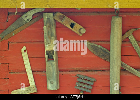 Vieux outils historique de charpentier et agriculteur accroché sur la paroi en bois rouge Banque D'Images