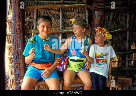 3 enfants sourire à la main les lauhala modélisation bandeaux tissés et tenir leur petit artisanat du Centre Culturel Polynésien, Oahu Banque D'Images