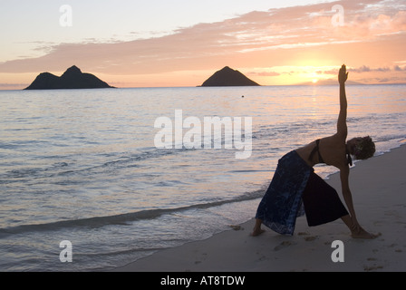 Silhouette d'une femme dans une pose de yoga avec un beau lever de soleil au loin. Photographiée au monde célèbre Lanikai beach Banque D'Images