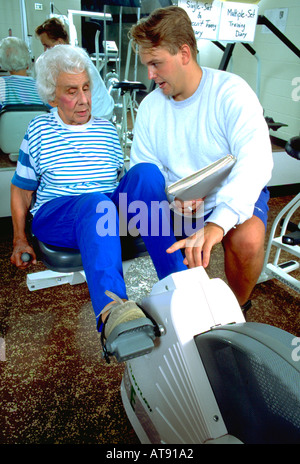 L'âge de 25 ans formateur Femme Âge 80 l'exercice de vélo sur un vélo couché la machine à Lynwood Centre de loisirs. St Paul Minnesota MN USA Banque D'Images