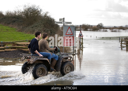 Deux mecs sur un quad bike s'attaquer au B4213 alors qu'il était fermé en raison d'inondations près de Apperley, Gloucestershire en mars 2007 Banque D'Images