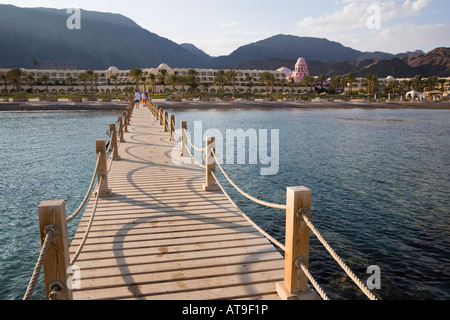 Jetée en bois avec vue sur la mer rouge en haut de la plage et hôtel de luxe resort en fin d'après-midi soleil Asie Egypte Sinai Taba Heights Banque D'Images