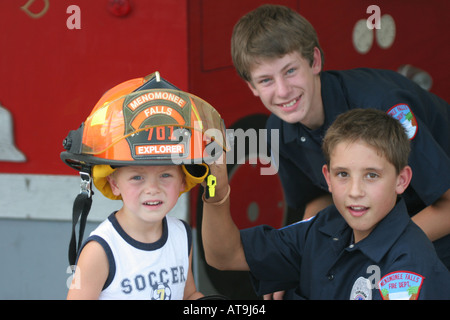 Deux futurs pompiers et un jeune garçon qui pourrait être un futur pompier et porte un casque explorateurs orange Banque D'Images