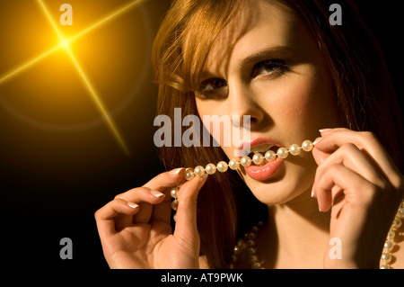 Woman biting un collier de perles Banque D'Images