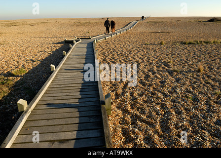 Deux couples de marcher le long de la promenade vers la mer à Dungeness, Kent, UK. Banque D'Images