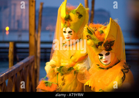 Carnaval de Venise Festival masque deux dames vêtues de costumes et masques jaune sur le bord du Grand Canal Venise Banque D'Images