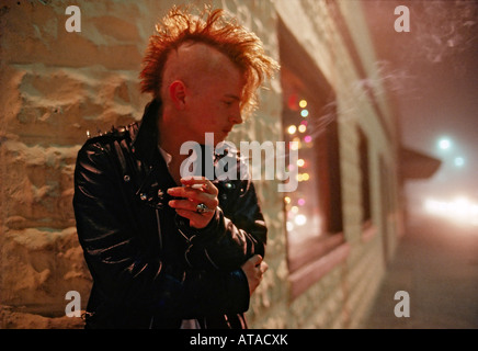 Jeune homme à la coupe mohawk fume une cigarette à l'extérieur d'un autre club discothèque à Jacksonville en Floride USA Banque D'Images