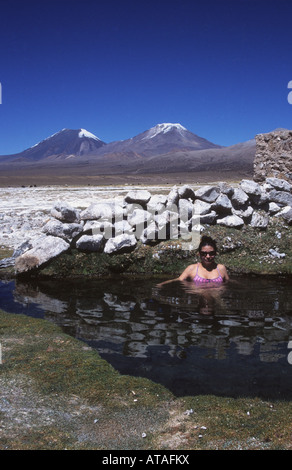 Hispanic woman enjoying les sources chaudes, volcans Payachatas en arrière-plan, le parc national de Sajama, Bolivie Banque D'Images