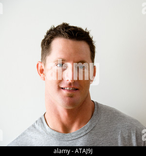Portrait de la tête et des épaules de l'homme en t shirt contre mur blanc Banque D'Images