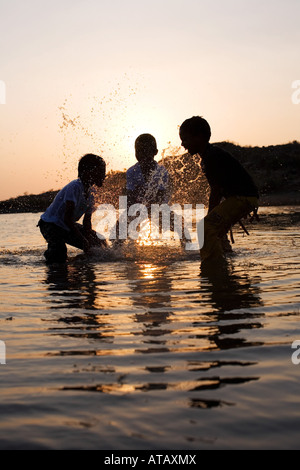 Trois garçons indiens ayant une lutte de l'eau dans un lac en Inde Banque D'Images