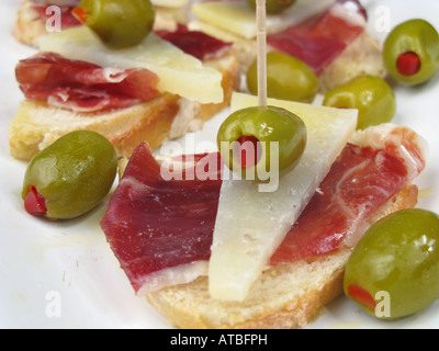 Style espagnol tapa de tranches de jambon iberico de bellota et fromage Manchego avec olives farcies poivrons pain croûté sur stonebaked. Banque D'Images