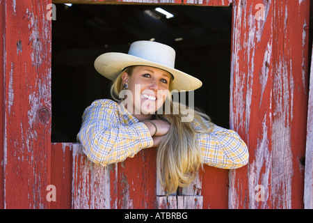 Cowgirl en regardant par la fenêtre à la porcherie, de l'Oregon, USA Banque D'Images