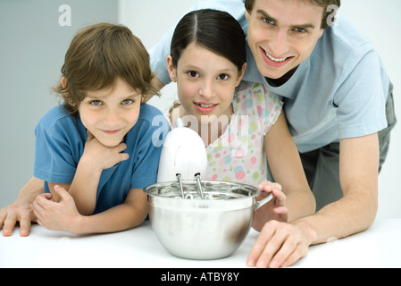 Son père et ses deux enfants, tous ensemble de cuisson smiling at camera Banque D'Images