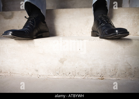 Businessman sitting on steps, portrait de pieds, low angle view Banque D'Images