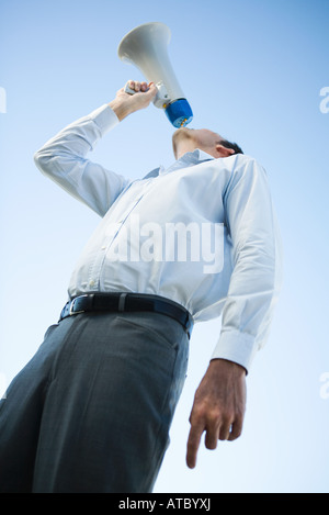 Businessman criant dans un mégaphone, low angle view Banque D'Images