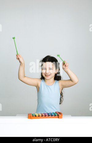Petite fille jouant du xylophone, bras levés, smiling Banque D'Images