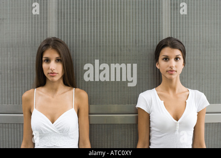 Teenage twin sisters côte à côte, looking at camera Banque D'Images