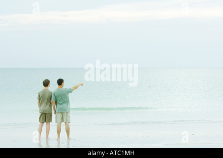 Père et fils se tenant ensemble à la plage, à la vue, à l'une dirigée Banque D'Images