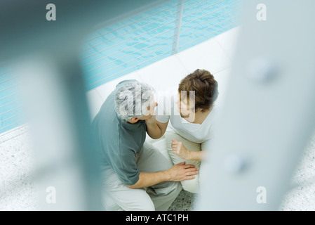 Couple assis à côté de piscine, high angle view, selective focus Banque D'Images