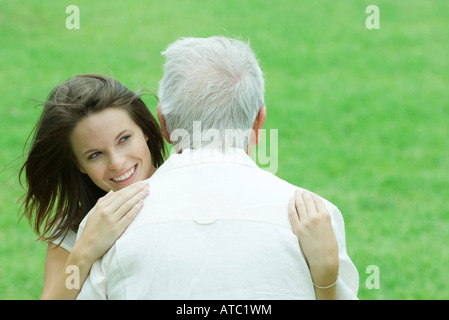 Teenage girl hugging son grand-père outdoors, smiling Banque D'Images