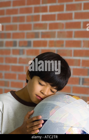 Boy leaning face contre bandées globe Banque D'Images