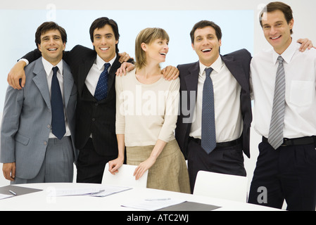 Équipe de partenaires d'affaires debout, les bras autour de l'autre, smiling, portrait Banque D'Images