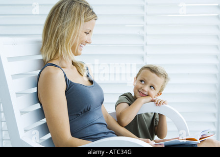 Femme assise dans la chaise à côté de son fils, holding book, à la fois in Banque D'Images