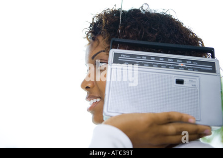 Woman holding radio à côté de l'oreille, smiling, portrait Banque D'Images