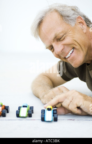 Man Playing with toy cars, smiling, close-up Banque D'Images