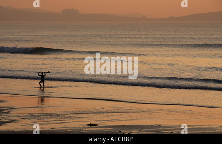 Un internaute se dresse sur la plage en regardant la mer au crépuscule Banque D'Images