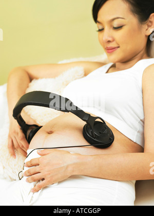 Femme enceinte avec un casque sur son ventre Banque D'Images