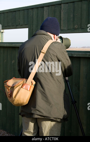 Observateur d'oiseaux côtiers, habillé en vert, à l'aide de la portée de cacher à Sandside, Marshside la réserve RSPB, Southport, Merseyside, Royaume-Uni Banque D'Images