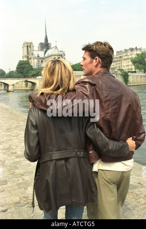 Couple en train de marcher bras autour de l'autre, l'église Notre-Dame en arrière-plan, Paris, France Banque D'Images