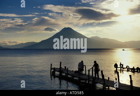 Les touristes à la fin d'une jetée qui se profile au coucher du soleil Panajachel Lac Atitlan Guatemala volcan San Pedro au-delà Banque D'Images