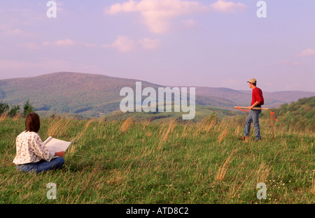Jeune couple travaillent avec leurs plans de maisons de rêve sur le futur site de la chambre Banque D'Images