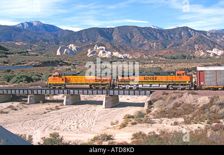 Deux moteurs de BNSF et transport 1033 4851 Nombre de nouvelles voitures à moteur pour traverser un pont au-dessus d'un lit de rivière à sec dans la vallée de San Bernardino Banque D'Images