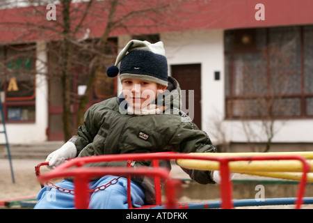 Jeune garçon sur un manège, les enfants jouant sur les merry-go-round in park Banque D'Images