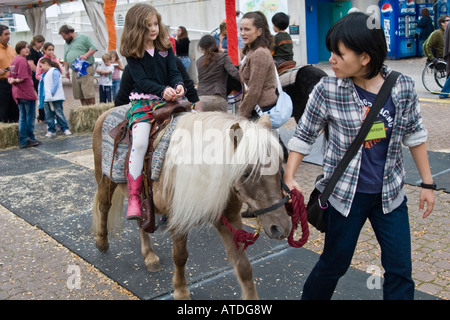 Équitation enfant un poney lors d'une récolte d'automne juste dirigé par un bénévole adolescents Toronto Canada Banque D'Images