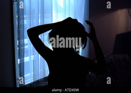 Silhouette de jeune femme faisant ses cheveux Banque D'Images