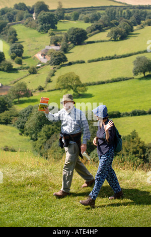 Une paire de randonneurs VAGUE COMME ILS TRAVERSENT LES ULEY BURY SUR LE COTSWOLD WAY PRÈS DE DURSLEY UK Banque D'Images