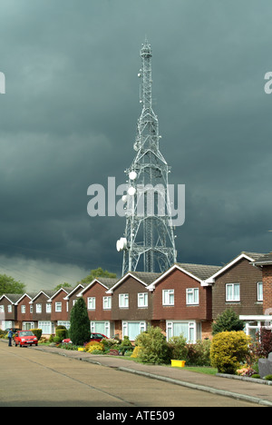 Mât de télécommunication s'élevant au-dessus de la rangée de maisons avec ciel de tempête Banque D'Images