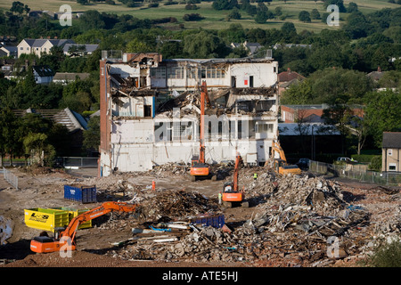 Vue en hauteur du site de démolition (coque d'usine vide, pelles hydrauliques à chenilles lourdes travaillant et démolissant des bâtiments, piles de gravats) - Guiseley, Angleterre, Royaume-Uni. Banque D'Images