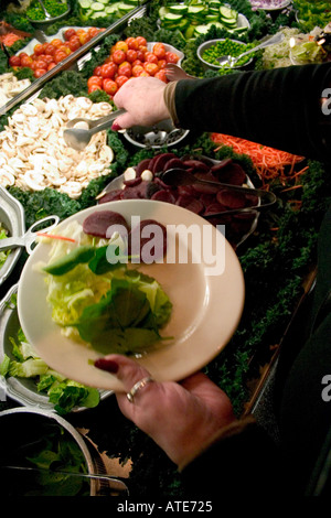 Femme sélection légumes au restaurant Ruby Tuesday bar à salades. Plymouth Minnesota MN USA Banque D'Images