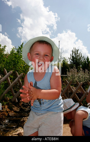 Jeune garçon clapping et rire à l'extérieur, le parc à thème des dinosaures, kid jouer avec l'eau Banque D'Images